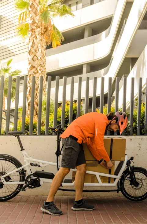 Een koerier laadt een pakket in de bak van zijn bakfiets