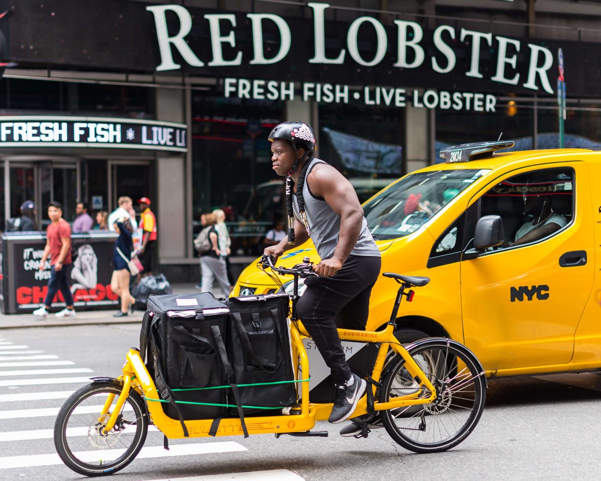 livreur roulant sur un vélo cargo professionnel jaune en ville