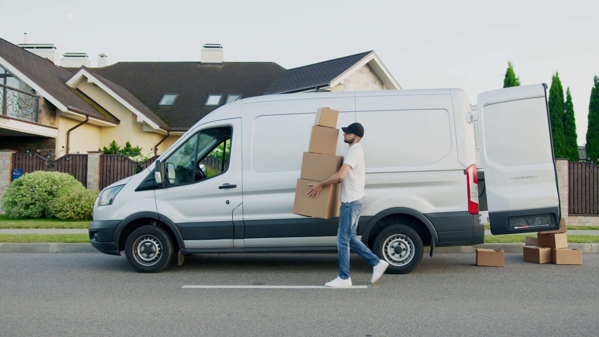 livreur portant des caisses en carton devant son véhicule utilitaire